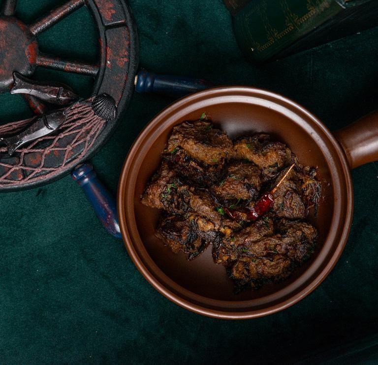 A clay pot of Indian street food on a green cloth