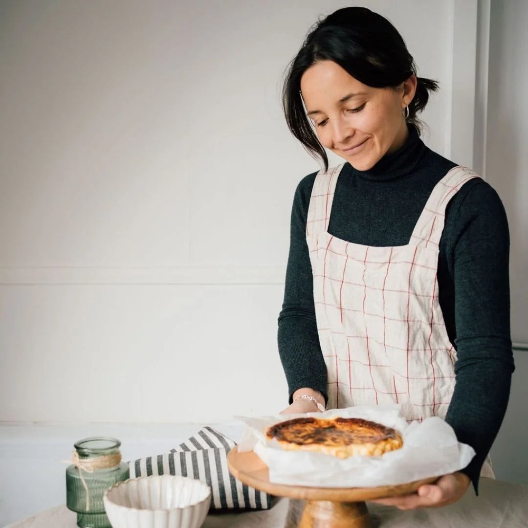 A baker carrying a cheesecake out of the kitchen