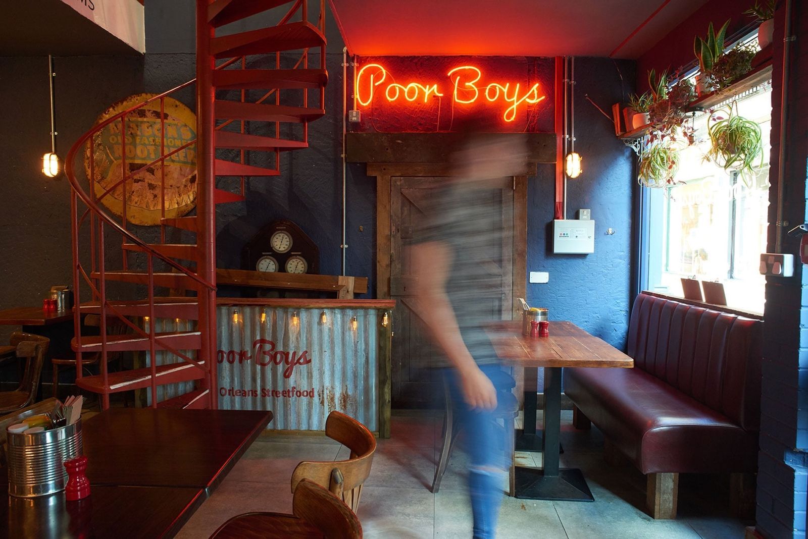 The Poor Boys dining room in Kingston, with a red spiral staircase, blue walls and the neon Poor Boys sign